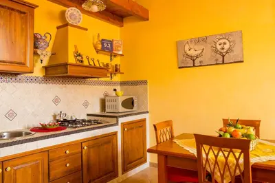 a kitchen with yellow walls and a table and a microwave at Casa Vacanze Caccamo Santa Lucia in Caccamo