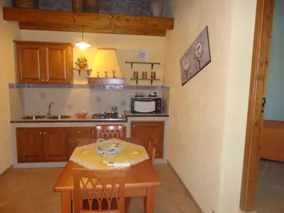 a kitchen with a wooden table and a table and chairs at Casa Vacanze Caccamo Santa Lucia in Caccamo