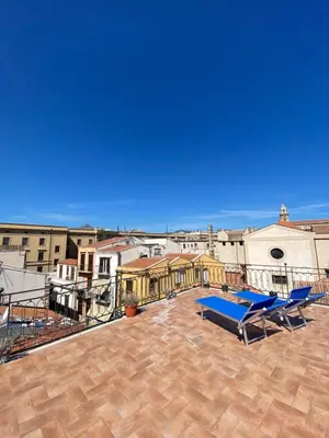 a large patio with two blue lounge chairs on a roof at Sunny loft with terrace and Jacuzzi in the city centre in Palermo