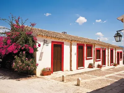 a building with red and white doors and flowers at Agriturismo Sirignano Wine Resort in Sirignano