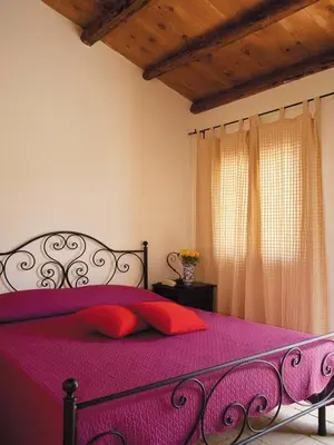a bedroom with a purple bed with a red pillow at Agriturismo Sirignano Wine Resort in Sirignano