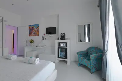 a white room with a bed and a chair at Palco Rooms&Suites in Palermo