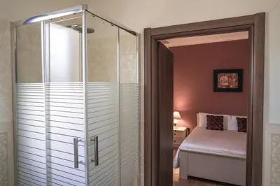 a glass shower door in a bedroom with a bed at Piano del Re rooms in Partinico
