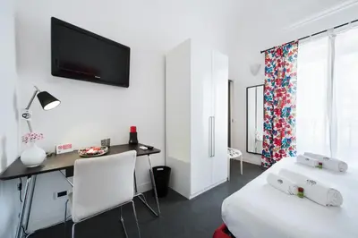 a room with a bed and a desk and a tv at White in Palermo