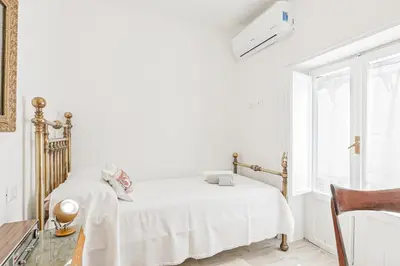 a white bedroom with a bed and a window at GuestHost - Palazzo dei Normanni Stylish Apartment in Palermo