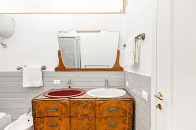 a bathroom with a sink and a mirror at GuestHost - Palazzo dei Normanni Stylish Apartment in Palermo