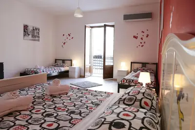 a bedroom with two beds and a balcony at Bahlara Case Vacanza in Palermo