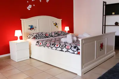 a bedroom with a white bed and red walls at Bahlara Case Vacanza in Palermo