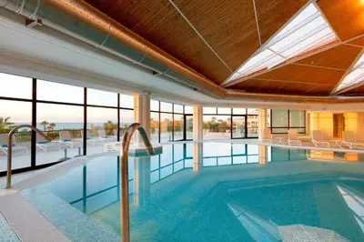 a pool in a building with a ceiling with windows at The Signature Level at Grand Palladium Sicilia Resort & Spa in Campofelice di Roccella