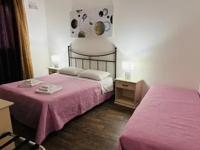 a bedroom with two beds with pink sheets and lamps at Triskell Camere & Relax in Castelluzzo