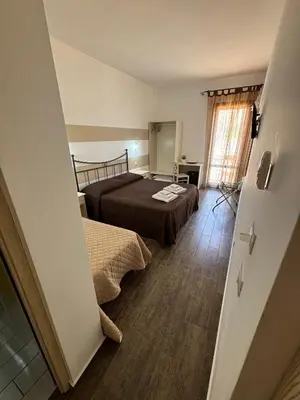 a hotel room with two beds and a window at Triskell Camere & Relax in Castelluzzo