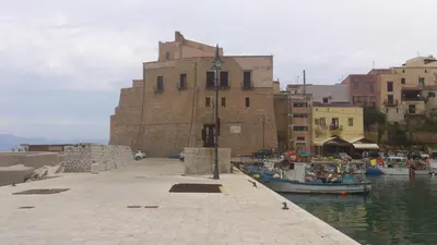 a building next to a harbor with boats in the water at Aziyz Camere in Castellammare del Golfo