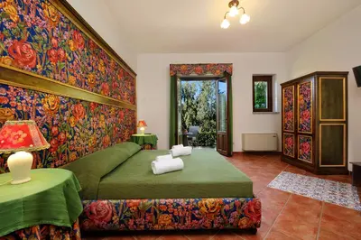 a bedroom with a green bed and a floral wall at Villa Dafne in Alia