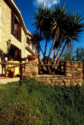 a stone wall with two palm trees next to a building at Villa Dafne in Alia