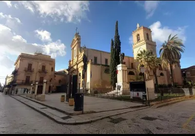 a large building with a clock tower on a street at Alcamo Rooms con GARAGE privato in Alcamo