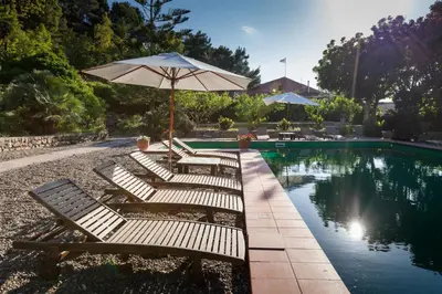 a row of chairs with an umbrella next to a pool at Masseria Pernice in Monreale