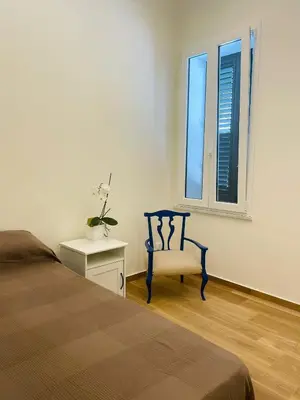 a bedroom with a bed and a chair and a window at Alemar Bed & Breakfast in Mondello
