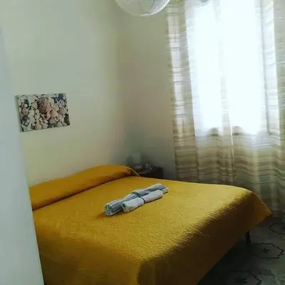 a bedroom with a yellow bed with two towels on it at Villa Giulia in Alcamo Marina