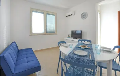 a living room with a table and blue chairs at Appartamento Darling in Isola delle Femmine