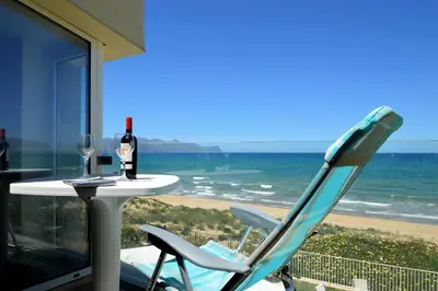 a table with a glass of wine and a chair on the beach at La Dimora di Venere in Alcamo