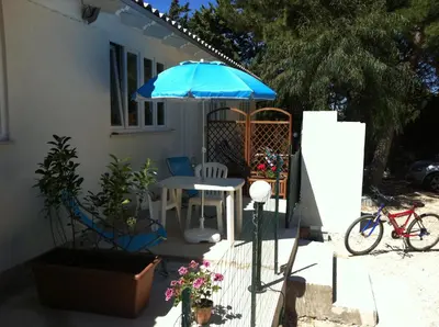 a patio with a table and a blue umbrella at Casa Vacanze Mari in San Vito lo Capo