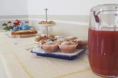 a table with cupcakes and a plate of muffins and a drink at Residenza Le Zagare in Castellammare del Golfo