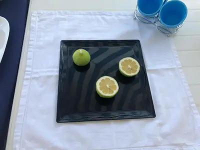 a black plate with an apple and lemon on a table at Blue Island Villa Caterina in Casteldaccia