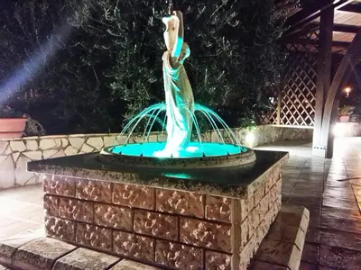 a statue of a mermaid in a fountain at night at B&B Al Giardino in Monreale