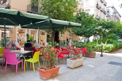 a patio with colorful chairs and tables and an umbrella at Operà in Palermo