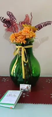 a green vase with orange flowers on a table at Casa Primavera in Palermo