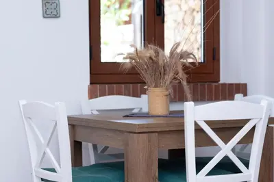 a wooden table with white chairs and a potted plant at Casa Ponente con Vista Mare a Macari in Macari
