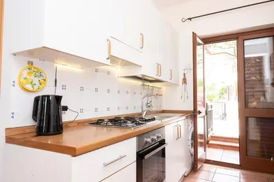 a kitchen with white cabinets and a stove top oven at Casa Ponente con Vista Mare a Macari in Macari