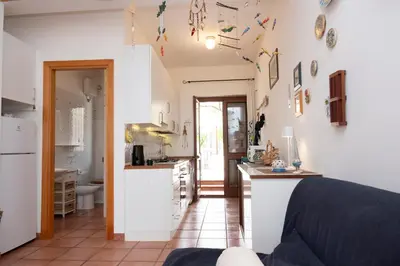 a kitchen and living room with white walls at Casa Ponente con Vista Mare a Macari in Macari