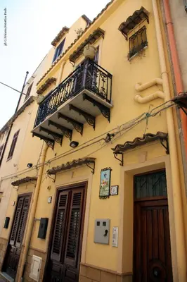 a yellow building with a balcony and a door at Donna Lia in Bagheria