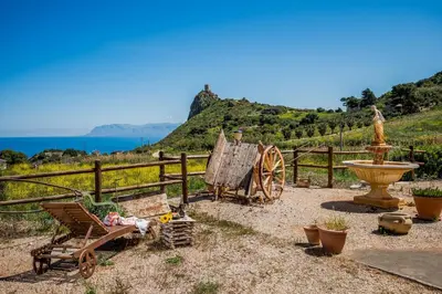 a garden with a wooden fence and a bench and a water fountain at Villa Elena vicino la Riserva naturale dello Zingaro in Scopello