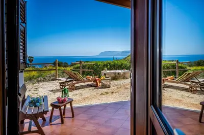 a view of the ocean from a patio door at Villa Elena vicino la Riserva naturale dello Zingaro in Scopello