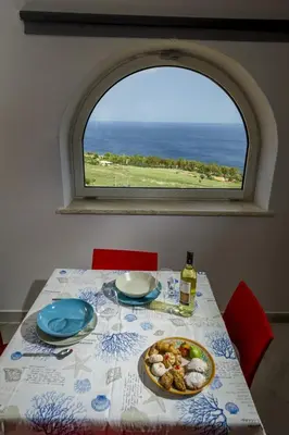 a kitchen with white cabinets and a view of the ocean at Villa Rosaria vicino la Riserva dello Zingaro in Scopello