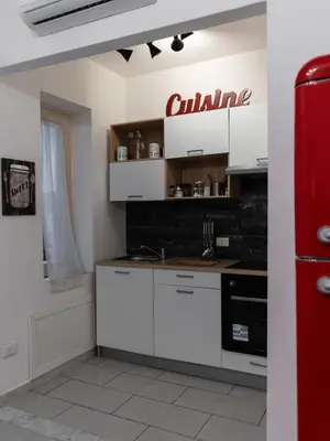a kitchen with white cabinets and a red sign on the wall at Casa in centro in Palermo