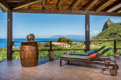 a deck with a chair and a table and a barrel at APT Villa Anna e APT Cantina Vito vicinissimi alla Riserva dello Zingaro in Scopello