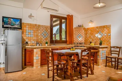 a kitchen with a table and a refrigerator at APT Villa Anna e APT Cantina Vito vicinissimi alla Riserva dello Zingaro in Scopello