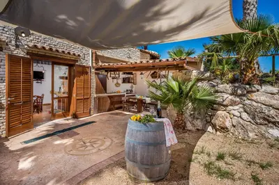 an outdoor patio with a table and a barrel at APT Villa Anna e APT Cantina Vito vicinissimi alla Riserva dello Zingaro in Scopello