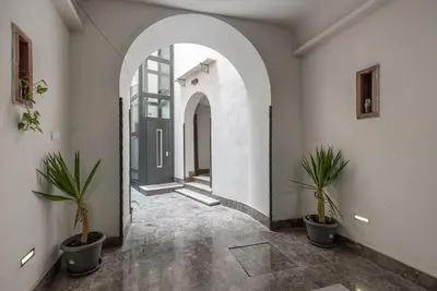 an arched hallway with potted plants and a black door at Casa La Pomelia in Palermo