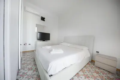 a white bedroom with a white bed and a tv at Appartamento 8 Pax in Villa Francesca by Ville in Palermo in Casteldaccia