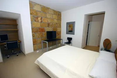 a bedroom with a white bed and a brick wall at Khalisah in Palermo