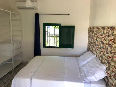 a bedroom with a white bed and a window at Egesta, villa with private pool in Calatafimi