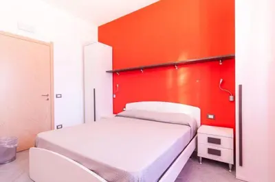 a bedroom with a white bed and an orange wall at B&B 