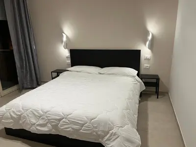 a bedroom with a white bed with two side tables at CESARE ROOMS in Palermo