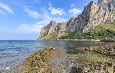 a rocky beach with a mountain in the background at Beautiful Apartment In Palermo Pa in Sferracavallo