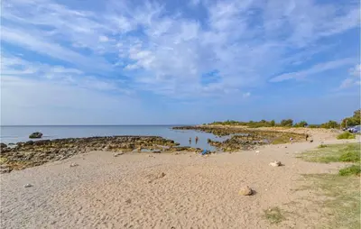 a beach with people standing on the sand and the water at Beautiful Apartment In Palermo Pa in Sferracavallo