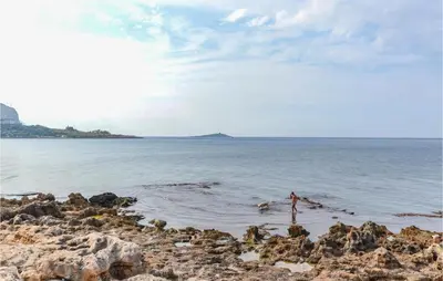 a person standing in the water on a rocky beach at Beautiful Apartment In Palermo Pa in Sferracavallo